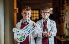 Two boys dressed as scientists holding a Tipperary Festival of Science sign