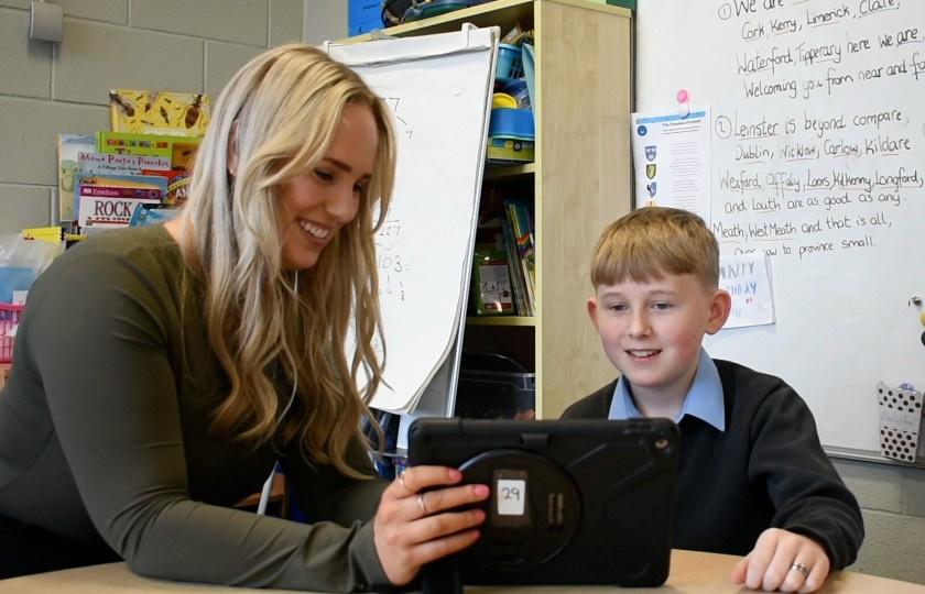 Female teacher holding iPad with male student