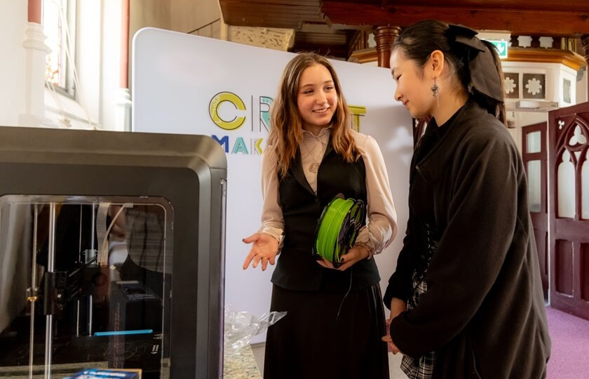 Two girls using the 3D printer